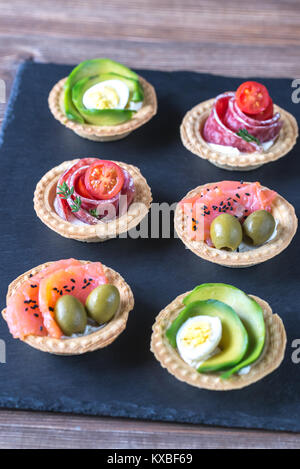 Törtchen mit verschiedenen Füllungen auf der Steintafel Stockfoto