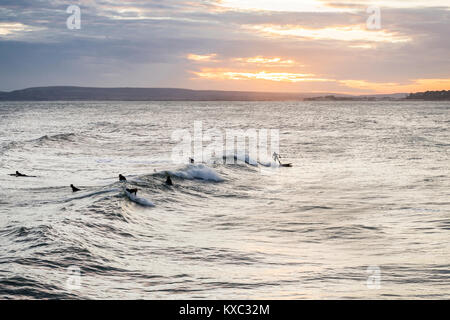 Golden Sunset über Bournemouth Strand/Meer mit Surfer Genießen der guten Swell, Bournemouth, Dorset, England, Großbritannien Stockfoto