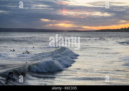 Golden Sunset über Bournemouth Strand/Meer mit Surfer Genießen der guten Swell, Bournemouth, Dorset, England, Großbritannien Stockfoto