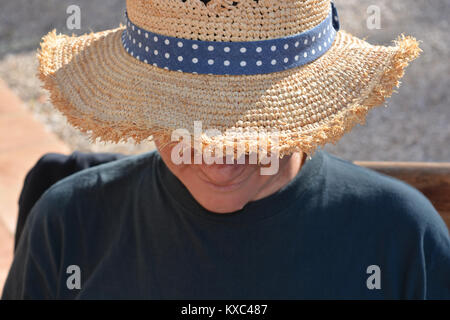 Frau draußen, trägt einen Strohhut in heißen, sonnigen Wetter Stockfoto