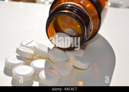 Gesundheitswesen und Medizin. Generische weiße Tabletten verschütten aus einem Glas Pilleflasche Stockfoto