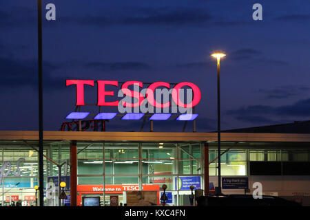 Leuchtet auf bei Tesco in der Nacht mit beleuchteten Tesco Schild am Supermarkt Tesco in Großbritannien. Stockfoto