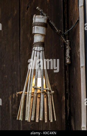 Eine historische Lampe mit einer modernen, hellen Lampe an der Wand des Hauses. Die alte Laterne auf eine Holzhütte hängt, Japan Landschaft.. Stockfoto