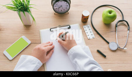Ärztin Notizen, medizinische Geschichte des Patienten oder Medizin Rezept auf Zwischenablage Papier während der medizinischen Untersuchung im Krankenhaus Büro Stockfoto