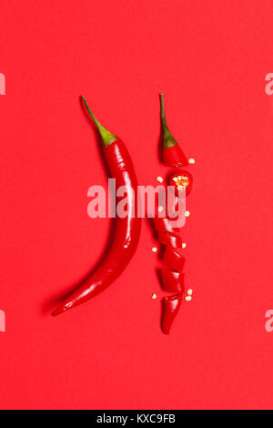 In Scheiben geschnittene Chilischote Pfeffer auf einem roten Hintergrund angeordnet Stockfoto