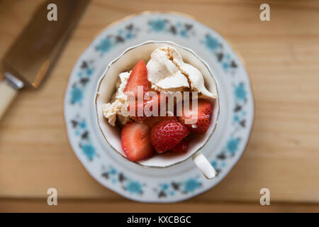 Frische Erdbeeren und Baiser Wüste serviert in einem Vintage Tee Tasse Stockfoto