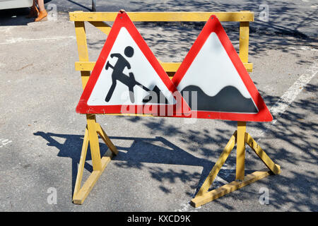 Gebogene hässlich Warnung Straßenschilder sind installiert auf der Straße repariert wird. Sonniger Frühlingstag urban geschossen Stockfoto