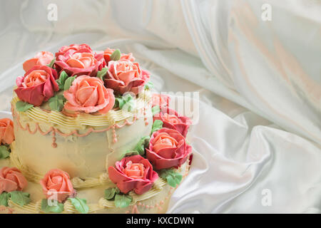 Torte mit Rosen closeup auf dem Hintergrund der Weiß Satin fabric Stockfoto