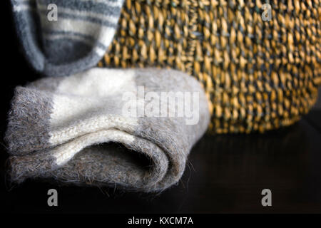 Wolle handgefertigt aus Gewirken winter Socken auf den Tisch gelegt, einen Weidenkorb in der verschwommenen Hintergrund Stockfoto