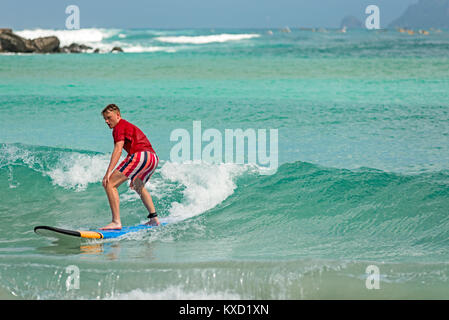 Junger Mann lernt, surfen Sie auf langen Board auf Lernende Wellen in paradiesischer Lage. Stockfoto