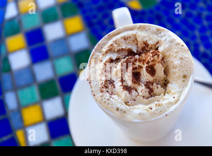 Tasse heißen Cappuccino steht auf einem Tisch im Stil der griechischen Mosaik. Ansicht von oben Stockfoto