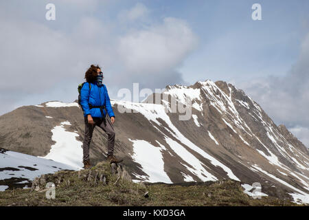 Die ganze Länge der Wanderer mit Schal über Mund auf Ansicht gegen Berge Stockfoto