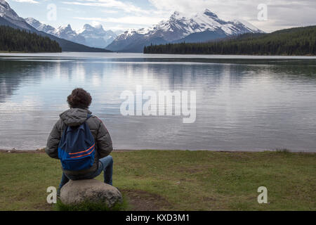 Wanderer mit Rucksack mit Blick auf Rock durch Maligne Lake Stockfoto