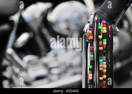 Bunte Perlen auf schwarzem Leder Quasten hängen von der Lenker eines amerikanischen Motorrad Stockfoto