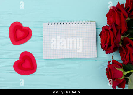 Rote Rosen, Herzen und Notizbuch aus Papier. Stockfoto