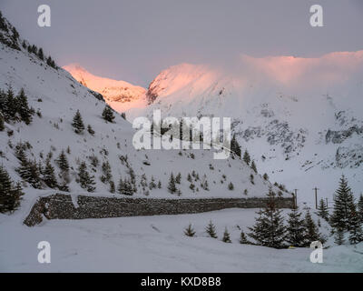 Weg bedeckt mit Schnee zwischen den Bergen Stockfoto