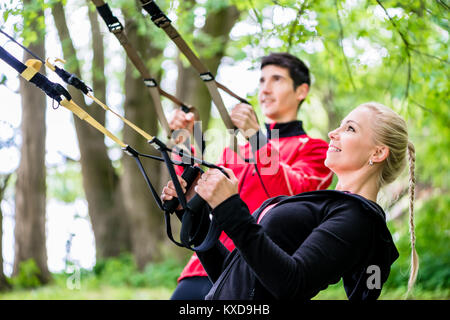 Sportliches Paar an der Sling Trainer Fitness tun Stockfoto