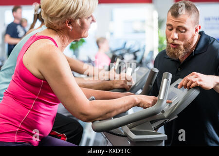 Personal trainer beauftragt Senior Frau über Spinnen in der Gy Stockfoto