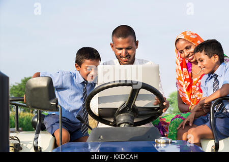 Ländliche Farmer Eltern Kinder Studenten sitzen Traktor laptop Farm Stockfoto