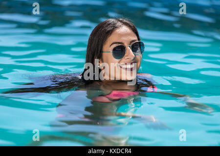 Junge Frau lächelnd im Pool Stockfoto