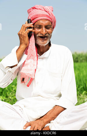 1 Indischen ländlichen Bauern alten Mann Telefon sitzen, Feld Stockfoto