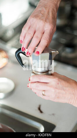 Eine ältere Frau bereitet einen Espresso mit einem traditionellen Bialetti Espressomaschine Stockfoto