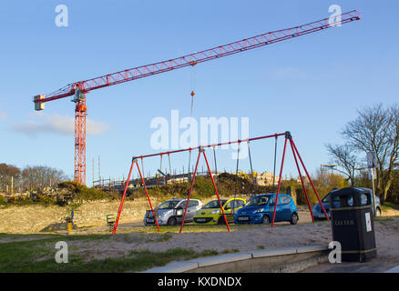 Eine hohe statische Turm Kran hoch über den Ufern Spielplatz der Kinder, die während der Nutzung auf einem Bauprojekt in Bangor County Down Nordirland Stockfoto