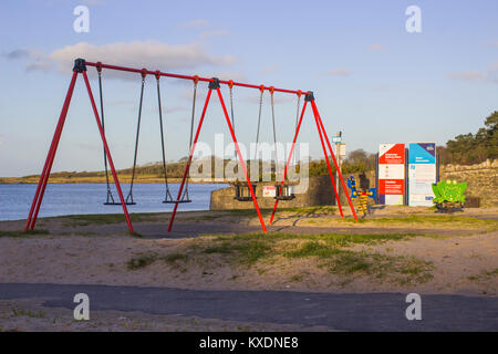 Der kleinen Kinderspielplatz mit Schaukeln und Sägen an der Banken im Bereich der Ballyholme Bangor County Down an einem Wintertag. Stockfoto