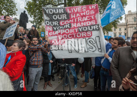 Die Menschen halten ein Banner Bitte um Unterstützung für die docators und die NHS am Ende der Ärzte zu speichern. März im Parlament Platz. Stockfoto