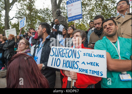 In der Masse um die Statue von Gandhi in Parliament Square hält eine Frau urgeons IST ein Plakat arbeiten noch 110 Stunden in der Woche Manchmal." Stockfoto