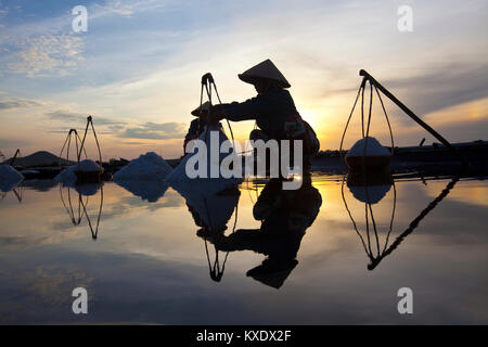 Weibliche Arbeitnehmer Ernte das Salz aus dem Meerwasser Teiche in der Nähe von Doc lassen, Vietnam. Sie arbeiten lange vor Sonnenaufgang, um die meisten der Hitze vermeiden Stockfoto