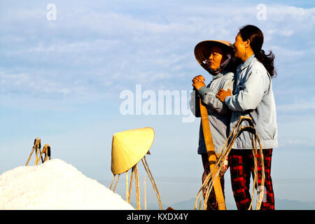 Entspannende weibliche Arbeitnehmer Ernte Salz aus Salz wasser Teiche in der Nähe von DocLet, Vietnam. Sie arbeiten lange vor Sonnenaufgang zu vermeiden die meisten der Hitze Stockfoto