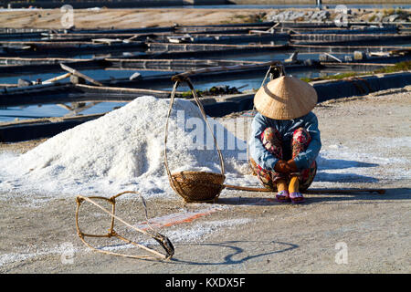 Einen müden Arbeiterin Ernte das Salz aus Salz wasser Teiche in der Nähe von DocLet, Vietnam. Sie arbeiten lange vor Sonnenaufgang, um die meisten der Hitze vermeiden Stockfoto