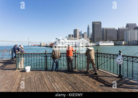San Francisco, USA - 2. Juli 2017: Leute angeln auf einem Pier am Embarcadero in San Francisco mit dem Financial District, die Bay Bridge ein Stockfoto