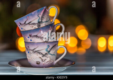 Antike japanische MORIAGE HANDBEMALTE Tasse & Untertasse - DRAGON WARE auf Holz Tisch mit Bokeh hellen Hintergrund Stockfoto
