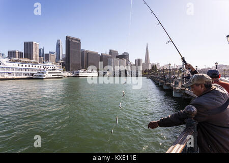 San Francisco, USA - 2. Juli 2017: Leute angeln auf einem Pier am Embarcadero in San Francisco mit dem Finanzviertel und der historischen Stockfoto