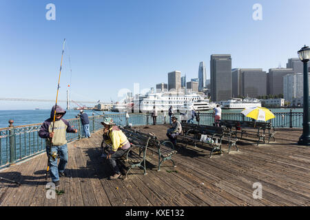 San Francisco, USA - 2. Juli 2017: Leute angeln auf einem Pier am Embarcadero in San Francisco mit dem Financial District, die Bay Bridge ein Stockfoto