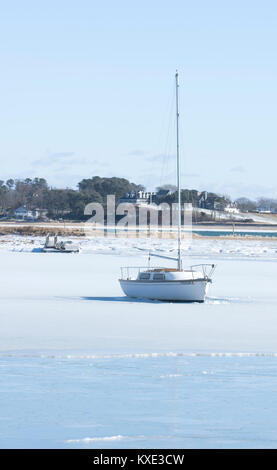 Warten auf Frühling. Ein Segelboot in runden Teich gefroren und Einlass in Harwich, Massachusetts, auf Cape Cod, USA Stockfoto