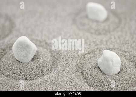 Weiße Kieselsteine in grau sand mit Kreisen Stockfoto