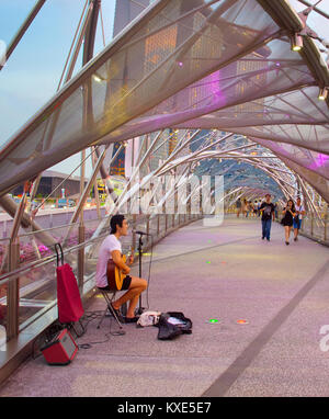 Singapur - Jan 13, 2017: Street Musiker Gitarre spielen auf dem Helix Bridge in Singapur. Helix Bridge ist eine Brücke in die Marina Bay. Stockfoto