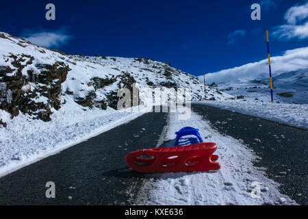 Schlitten. Zwei Schlitten, Rot und Blau, auf einer verschneiten Straße. Stockfoto