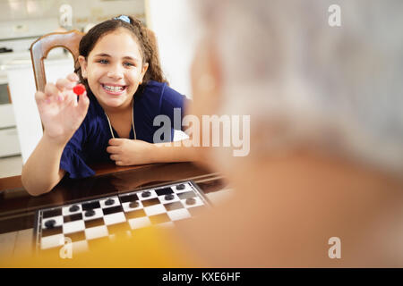 Oma spielen Checkers Board Game mit Enkeltochter zu Hause Stockfoto