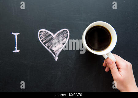 Ansicht von oben Ich liebe herz doodle Zeichnung auf schiefertafel mit der menschlichen Hand, die Tasse Kaffee Stockfoto