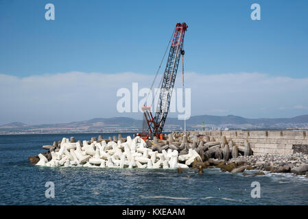 Kapstadt Südafrika. Dezember 2017. Kran platzieren Tetrapods, konkreten Bausteinen die Kaimauer rund um den Hafen zu schützen. Stockfoto