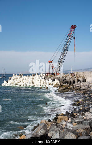 Kapstadt Südafrika. Dezember 2017. Kran platzieren Tetrapods, konkreten Bausteinen die Kaimauer rund um den Hafen zu schützen. Stockfoto