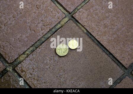 Australische Münzen im Freien bei Regen im Tageslicht. Australische Geld auf nasser Fahrbahn mit kleinen Wassertropfen auf einem dollar Münze und zwei Dollar Münze. Stockfoto