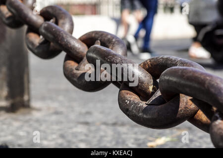 Nahaufnahme von rostigem Metall Kette links auf einer unscharfen Marktplatz im Hintergrund Stockfoto