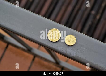 Australische Münzen im Freien bei Regen im Tageslicht. Australische Geld auf nasser Fahrbahn mit kleinen Wassertropfen auf einem dollar Münze und zwei Dollar Münze. Stockfoto