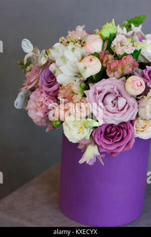 Die schönen Blumenstrauß im lila Kasten auf grauem Hintergrund Stockfoto