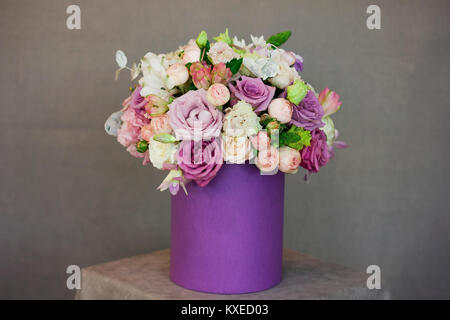 Die schönen Blumenstrauß im lila Kasten auf grauem Hintergrund Stockfoto
